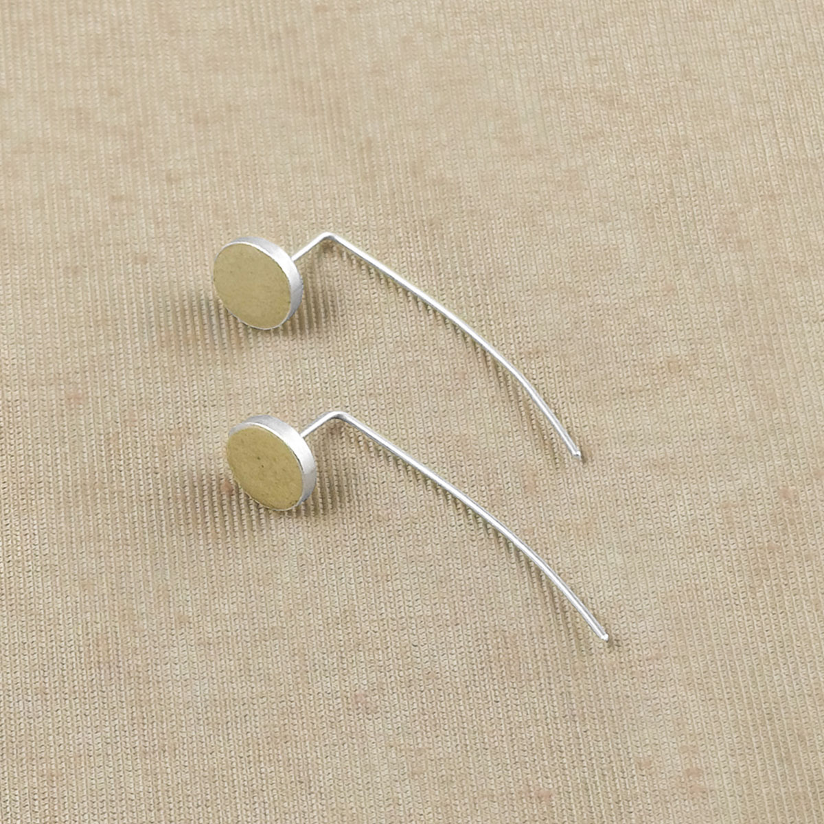 Sterling silver handmade geometric drop earrings laying on surface