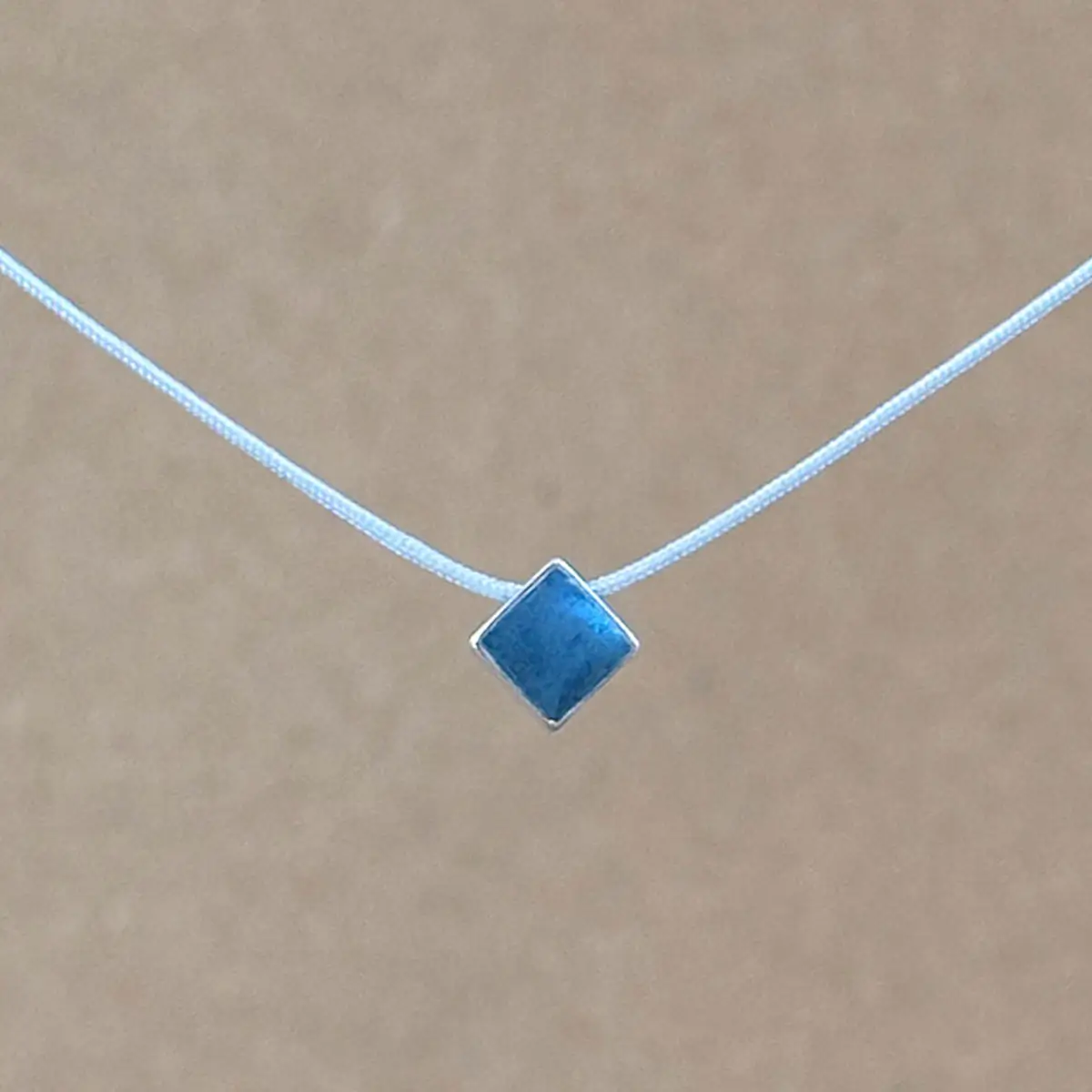 Teal Point necklace — small diamond-shaped teal clay pendant in a sterling silver frame on a light gray kumihimo cord.