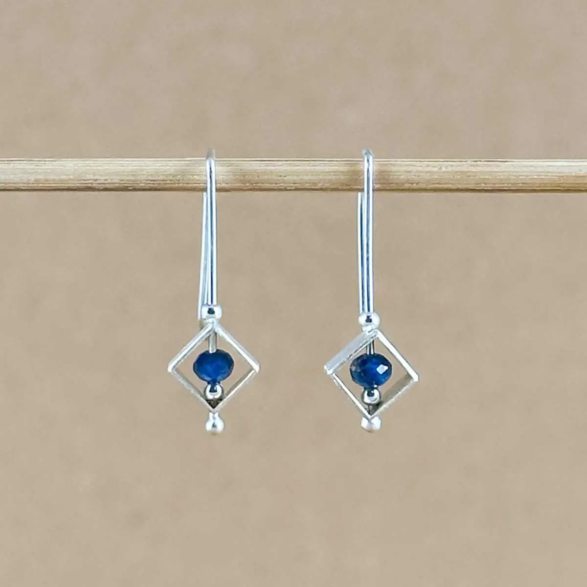 Pair of Lapis Frame Earrings hanging side by side, with diamond-shaped sterling silver frames and lapis lazuli beads centered inside.
